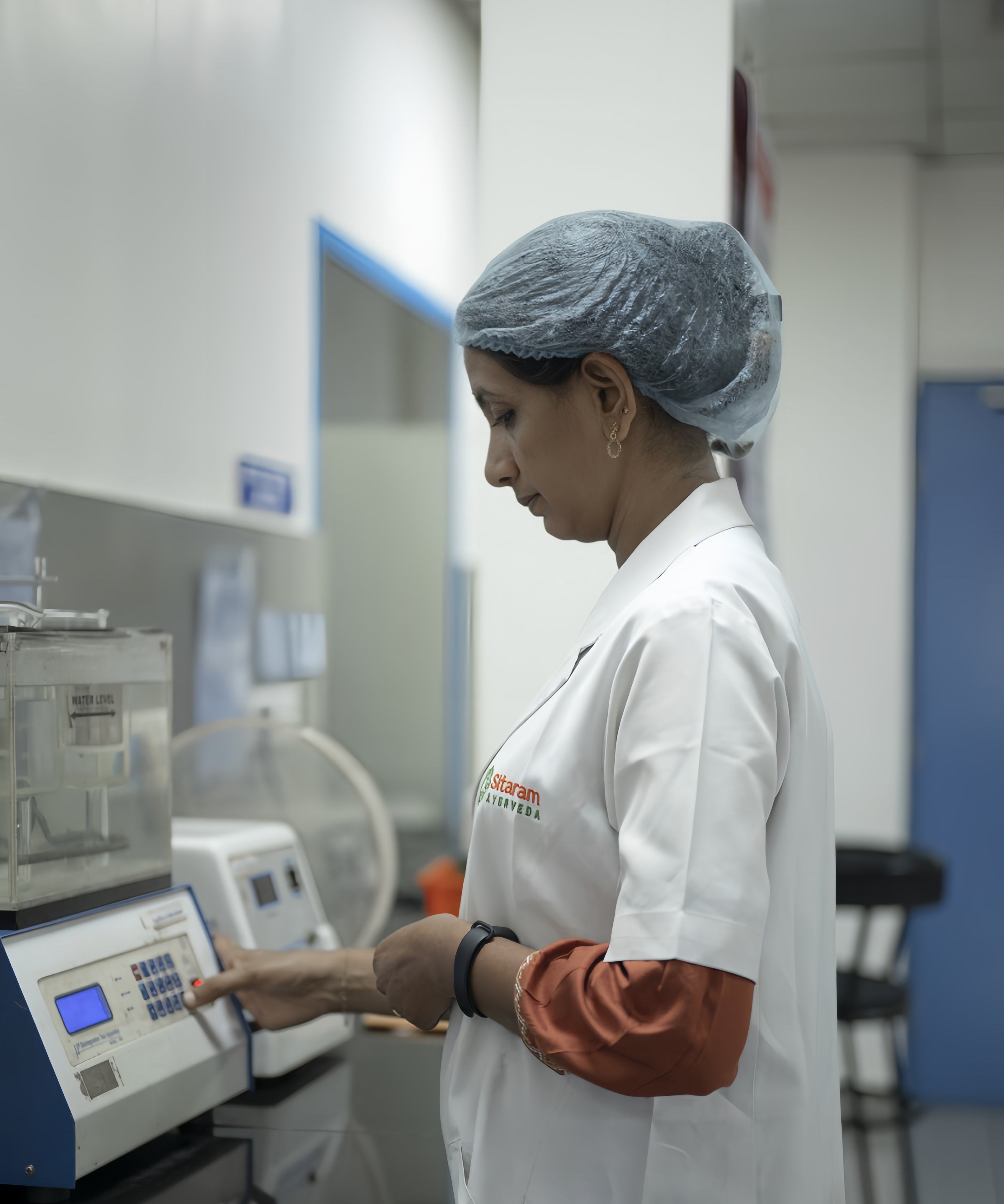 Sitaram Ayurveda Europe R&D technician in a lab coat using a machine in a laboratory setting
